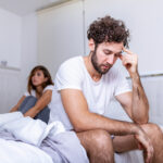 Beautiful girl and a frustrated man sitting in bed and not looking at each other